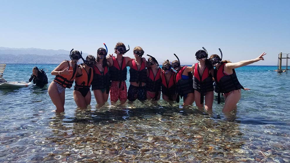 Group shot, teens standing in water with scuba gear
