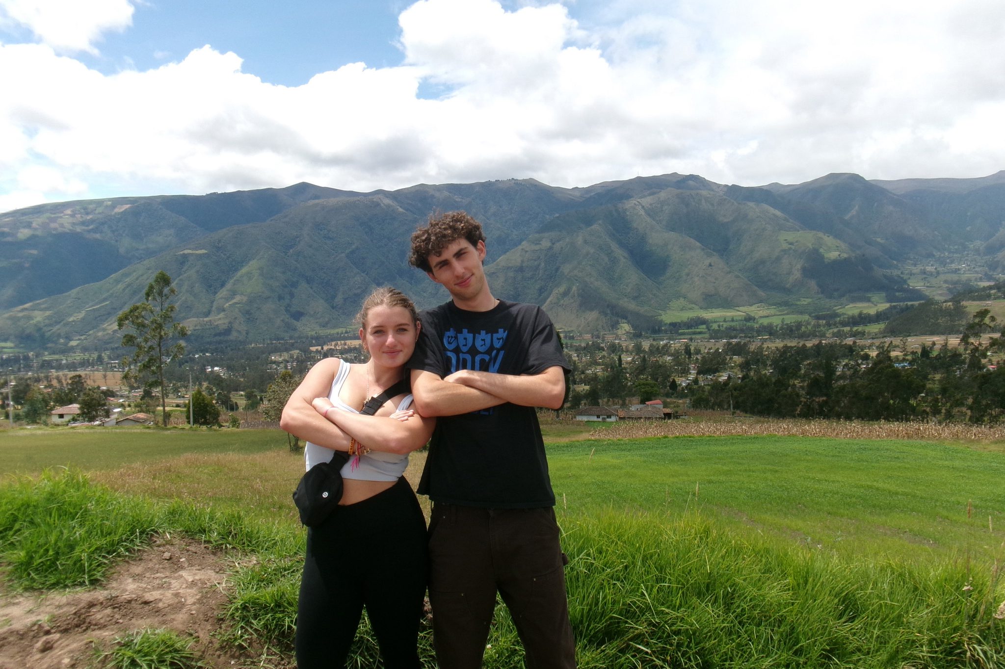 Two teens pose with arms crossed in front of a beautiful landscape of mountains and fields during their BBYO summer adventure